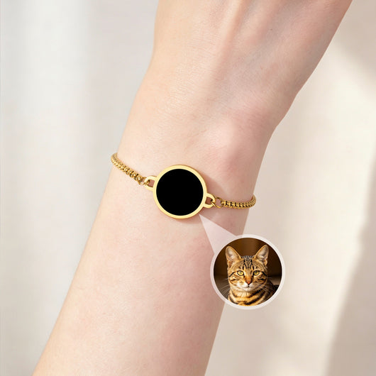 Gold bracelet with a dark medallion hiding a cat photo