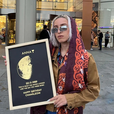 Woman holding a personalized moon phase print in a natural wood frame